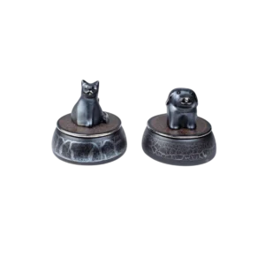 Figuras decorativas de un gato y un perro en bases redondas, fabricadas en material oscuro con detalles brillantes, ideales para la decoración del hogar.
