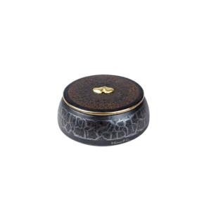 Caja decorativa de cerámica negra con un diseño agrietado y tapa marrón, adornada con un detalle dorado en forma de gota. Ideal para almacenamiento y decoración de interiores.